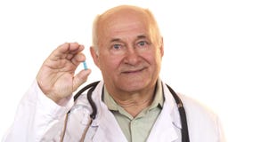 Doctor de sexo masculino mayor alegre que sostiene una píldora azul fotografía de archivo Doctor de sexo masculino mayor alegre que sostiene una píldora azul fotografía de archivo