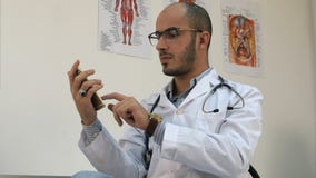 Doctor de sexo masculino serio que manda un SMS en un smartphone imagenes de archivo Doctor de sexo masculino serio que manda un SMS en un smartphone imagenes de archivo