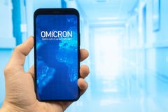Doctor hand holds mobile phone with text Omicron variant of coronavirus. Hospital background. Design for news web sites