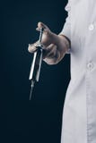 Doctor holding a big stainless steel syringe stock image Doctor holding a big stainless steel syringe stock image