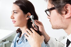 Doctor holding otoscope and Examining a woman patient ear royalty free stock images Doctor holding otoscope and Examining a woman patient ear royalty free stock images