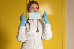 Doctor in nitrile gloves and stethoscope covering face with a mask