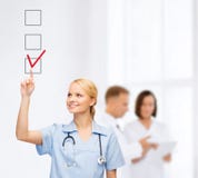 Doctor or nurse drawning checkmark into checkbox stock photos Doctor or nurse drawning checkmark into checkbox stock photos