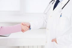 Doctor and patient in the office shaking hands, healthcare and assistance concept.Medical insurance. Doc sitting in cabinet stock photo Doctor and patient in the office shaking hands, healthcare and assistance concept.Medical insurance. Doc sitting in cabinet stock photo