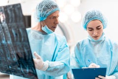 Doctor preocupante que mira a su colega mientras que muestra resultados de la radiografía imagen de archivo Doctor preocupante que mira a su colega mientras que muestra resultados de la radiografía imagen de archivo