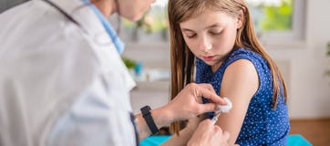 Doctor que da a una chica joven un tiro vaccíneo fotografía de archivo Doctor que da a una chica joven un tiro vaccíneo fotografía de archivo