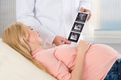 Doctor Showing Ultrasound Scan To Pregnant Woman