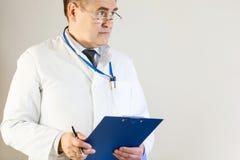 A doctor in a white coat looks into the distance and holds a folder and a pen royalty free stock images A doctor in a white coat looks into the distance and holds a folder and a pen royalty free stock images