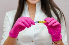 Doctor woman with black hair and purple gloves shows syringe
