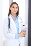 Doctor woman using tablet computer while standing straight near window in hospital. Happy physician at work. Medicine stock images Doctor woman using tablet computer while standing straight near window in hospital. Happy physician at work. Medicine stock images