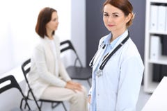 Doctor woman at work. Portrait of female physician cheerful smiling while standing near reception desk at clinic or stock photo Doctor woman at work. Portrait of female physician cheerful smiling while standing near reception desk at clinic or stock photo