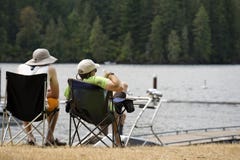 Dois amigos estão relaxando na costa do lago da montanha na floresta foto de stock Dois amigos estão relaxando na costa do lago da montanha na floresta foto de stock