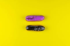 Dois bonitos e eclairs deliciosos em um fundo amarelo brilhante imagens de stock Dois bonitos e eclairs deliciosos em um fundo amarelo brilhante imagens de stock