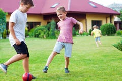 Dois filhos felizes que jogam o futebol com seu pai no jardim próximo imagem de stock Dois filhos felizes que jogam o futebol com seu pai no jardim próximo imagem de stock
