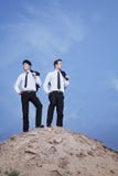 Dois homens de negócios novos que estão na parte superior do monte no deserto fotografia de stock Dois homens de negócios novos que estão na parte superior do monte no deserto fotografia de stock