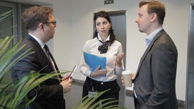 Dois homens e a mulher estão falando, rindo ao estar na entrada da empresa video estoque Dois homens e a mulher estão falando, rindo ao estar na entrada da empresa video estoque