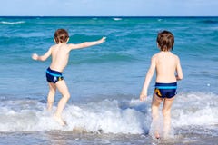 Dois meninos da criança que correm na praia do oceano Crianças pequenas que têm o divertimento fotografia de stock royalty free Dois meninos da criança que correm na praia do oceano Crianças pequenas que têm o divertimento fotografia de stock royalty free
