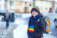Dois meninos das crianças da classe elementar que andam à escola durante a queda de neve Crianças felizes que têm o divertimento imagens de stock Dois meninos das crianças da classe elementar que andam à escola durante a queda de neve Crianças felizes que têm o divertimento imagens de stock