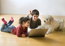 Dois miúdos com computador portátil e um cão imagens de stock royalty free Dois miúdos com computador portátil e um cão imagens de stock royalty free