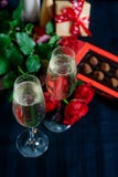 Dois vidros do champanhe, de rosas vermelhas e de doces em um fundo preto foto de stock royalty free Dois vidros do champanhe, de rosas vermelhas e de doces em um fundo preto foto de stock royalty free