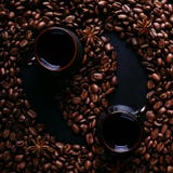 Dois xícaras de café, anises de estrela e feijões de café em uma bancada escura da cozinha sob a forma de Feng Shui Especiarias p foto de stock Dois xícaras de café, anises de estrela e feijões de café em uma bancada escura da cozinha sob a forma de Feng Shui Especiarias p foto de stock