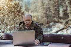 Dojrzały męski myśliwy z pastylka laptopem i komputerem osobistym fotografia stock Dojrzały męski myśliwy z pastylka laptopem i komputerem osobistym fotografia stock