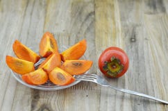 Dojrzały persimmon, talerz z słodkim cięciem i deserowy rozwidlenie na drewnianym stole obraz stock Dojrzały persimmon, talerz z słodkim cięciem i deserowy rozwidlenie na drewnianym stole obraz stock