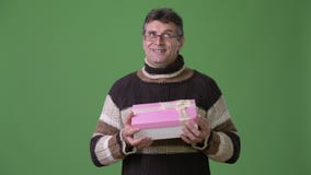 Dojrzały przystojny mężczyzna jest ubranym turtleneck pulower przeciw zielonemu tłu zbiory Dojrzały przystojny mężczyzna jest ubranym turtleneck pulower przeciw zielonemu tłu zbiory