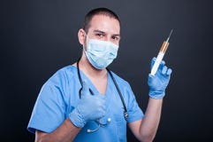 Dokter het dragen schrobt het tonen van spuit en gelijkaardig gebaar stock afbeelding Dokter het dragen schrobt het tonen van spuit en gelijkaardig gebaar stock afbeelding