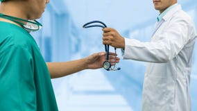 Doktor som ger stetoskopet till kirurgen Referral royaltyfria bilder Doktor som ger stetoskopet till kirurgen Referral royaltyfria bilder