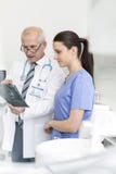Doktor som undersöker den medicinska röntgenstrålen med sjuksköterskan på den tand- kliniken arkivbild Doktor som undersöker den medicinska röntgenstrålen med sjuksköterskan på den tand- kliniken arkivbild