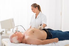 Doktor Using Ultrasound Scan auf Unterleib des männlichen Patienten Stockfotografie Doktor Using Ultrasound Scan auf Unterleib des männlichen Patienten Stockfotografie