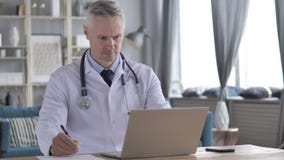 Doktor Writing Medical Report des Patienten und des Arbeitens an Laptop stock video Doktor Writing Medical Report des Patienten und des Arbeitens an Laptop stock video