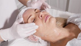 Doktorkosmetiker entfernt den Make-uppatienten, der auf einer speziellen Tabelle liegt stock footage Doktorkosmetiker entfernt den Make-uppatienten, der auf einer speziellen Tabelle liegt stock footage
