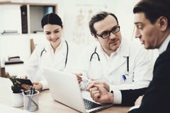 Doktorn i exponeringsglas råder tålmodigt sammanträde på tabellen med bärbara datorn i medicinskt kontor arkivfoto Doktorn i exponeringsglas råder tålmodigt sammanträde på tabellen med bärbara datorn i medicinskt kontor arkivfoto