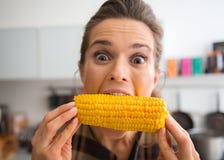 Dokuczający, szczęśliwa kobieta bierze dużego kąsek kukurudza na cob Fotografia Stock Dokuczający, szczęśliwa kobieta bierze dużego kąsek kukurudza na cob Fotografia Stock