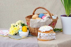 Dolce di Pasqua e il bascket con le uova colorate ed i fiori gialli, sulla tavola fotografia stock libera da diritti Dolce di Pasqua e il bascket con le uova colorate ed i fiori gialli, sulla tavola fotografia stock libera da diritti
