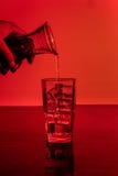 Dolewanie alkohol w szklany pełnym lód z obrazy stock Dolewanie alkohol w szklany pełnym lód z obrazy stock