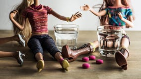 Doll die met schoten van wodka en roze pillen partying stock fotografie Doll die met schoten van wodka en roze pillen partying stock fotografie