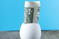 1 dollar bill in an egg shell. On a turquoise background. The co stock photos 1 dollar bill in an egg shell. On a turquoise background. The co stock photos