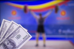 Dollari dei soldi sui precedenti della TV su cui sollevamento pesi di manifestazione, sport che scommettono, sollevamento pesi, d fotografia stock Dollari dei soldi sui precedenti della TV su cui sollevamento pesi di manifestazione, sport che scommettono, sollevamento pesi, d fotografia stock