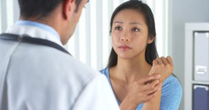 Dolor de descripción paciente asiático de la muñeca al doctor foto de archivo libre de regalías Dolor de descripción paciente asiático de la muñeca al doctor foto de archivo libre de regalías