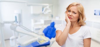 Dolor de muelas sufridor de la mujer infeliz en la oficina dental imagen de archivo libre de regalías Dolor de muelas sufridor de la mujer infeliz en la oficina dental imagen de archivo libre de regalías