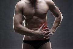 Dolor en el lado izquierdo Carrocería masculina muscular Culturista hermoso que presenta en fondo gris fotografía de archivo libre de regalías Dolor en el lado izquierdo Carrocería masculina muscular Culturista hermoso que presenta en fondo gris fotografía de archivo libre de regalías