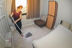 Domestica asiatica Cleaning Service con il pavimento di pulizia di zazzera su una camera da letto fotografia stock Domestica asiatica Cleaning Service con il pavimento di pulizia di zazzera su una camera da letto fotografia stock