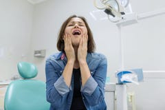 Donna adulta che soffre dal mal di denti e che sporge querela durante la visita al dentista professionista fotografia stock libera da diritti Donna adulta che soffre dal mal di denti e che sporge querela durante la visita al dentista professionista fotografia stock libera da diritti