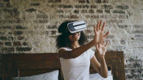 Donna afroamericana riccia che ottiene esperienza facendo uso dei vetri della cuffia avricolare di VR 360 di realtà virtuale a ca stock footage Donna afroamericana riccia che ottiene esperienza facendo uso dei vetri della cuffia avricolare di VR 360 di realtà virtuale a ca stock footage