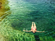 Donna che fa galleggiare in chiaro acqua di un fiume della montagna fotografia stock libera da diritti Donna che fa galleggiare in chiaro acqua di un fiume della montagna fotografia stock libera da diritti