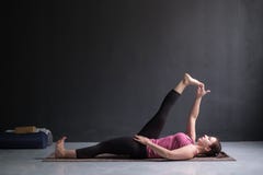 Donna che fa padangusthasana di Supta di asana di yoga o mano adagiantesi alla posa dell'alluce fotografie stock libere da diritti Donna che fa padangusthasana di Supta di asana di yoga o mano adagiantesi alla posa dell'alluce fotografie stock libere da diritti