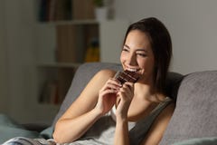 Donna che gode mangiando cioccolato nella notte fotografia stock Donna che gode mangiando cioccolato nella notte fotografia stock
